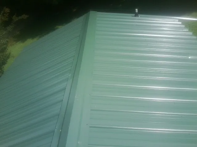 New green metal panels meeting at the ridge of a roof — Flat Roof Repair work by our crew in Boulevard