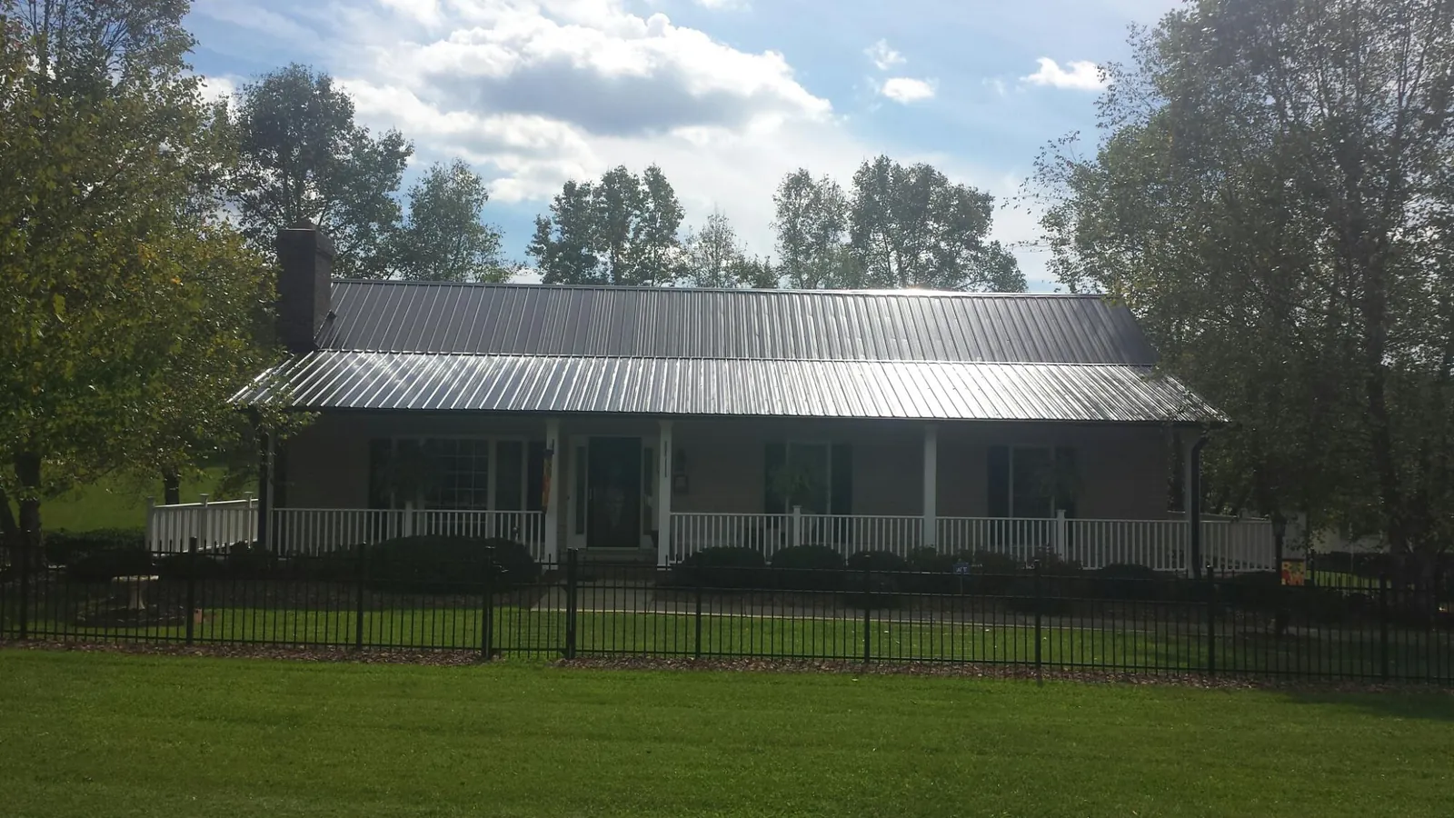 Gray metal roof on a brick ranch with a full width front porch — Gutter Guard Installation work by our crew in Boulevard