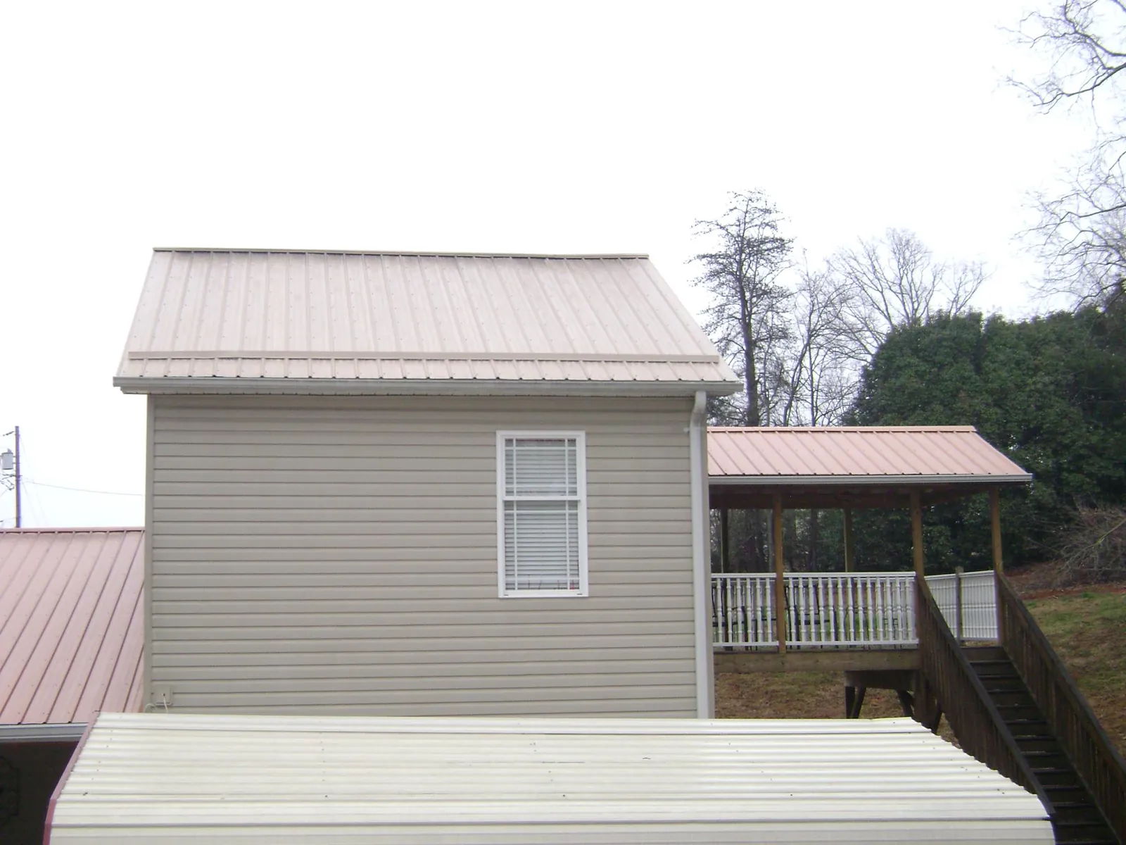 Tan metal roofs on a two story addition and attached porch, from a Roof Replacement job in Boulevard