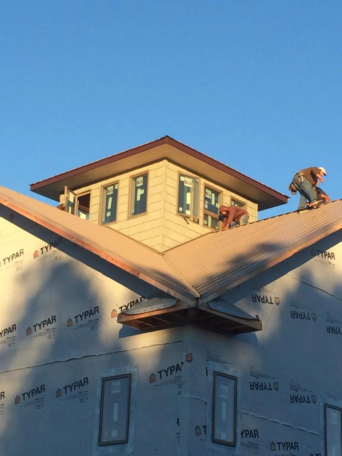 Roofers working around a rooftop cupola on a new metal roof at sunset — Roof Waterproofing in Boulevard by Roofing Brothers
